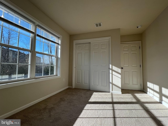 unfurnished bedroom with light colored carpet, a closet, visible vents, and baseboards