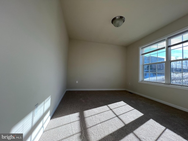 empty room with baseboards and dark colored carpet