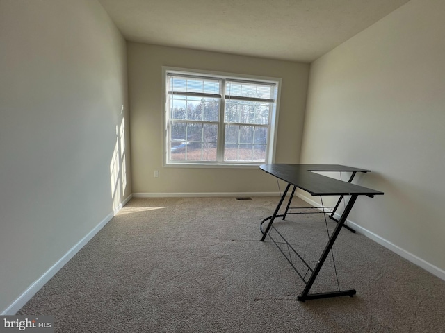 unfurnished office with visible vents, baseboards, and carpet flooring