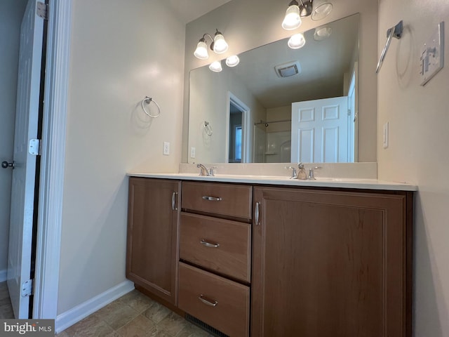 bathroom with double vanity, a sink, visible vents, and baseboards