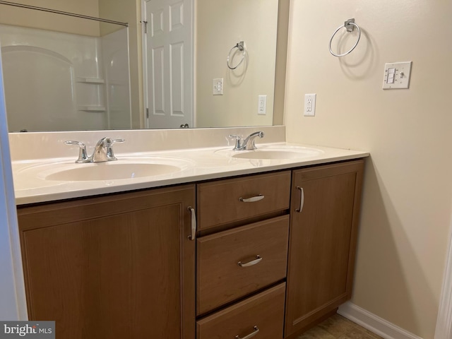 full bath with a sink, baseboards, and double vanity