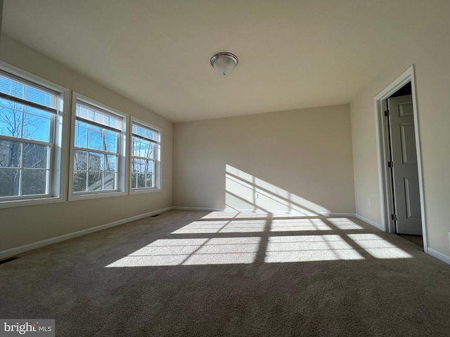 empty room featuring light carpet, visible vents, and baseboards