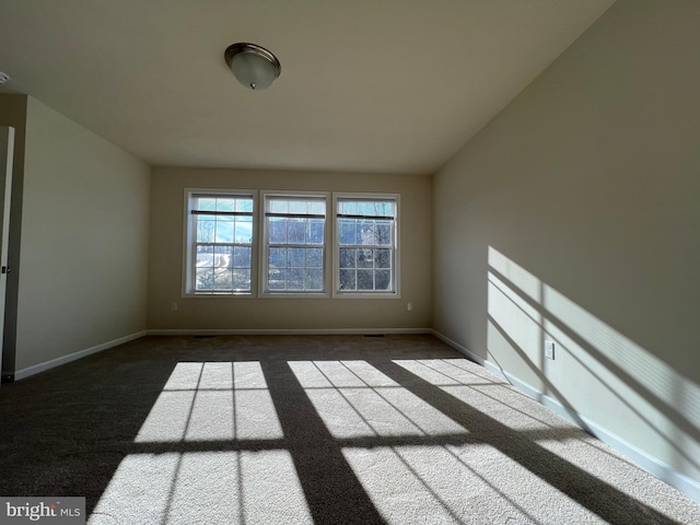 empty room featuring carpet and baseboards