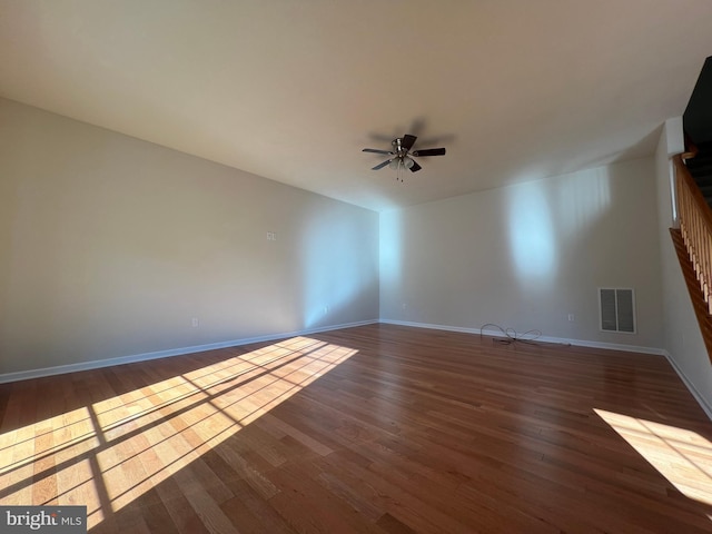 spare room featuring dark wood-style floors, visible vents, baseboards, and a ceiling fan