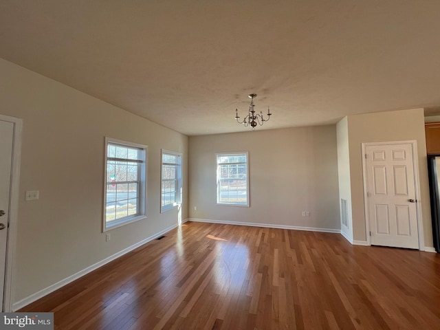 spare room with light wood finished floors, baseboards, and a chandelier