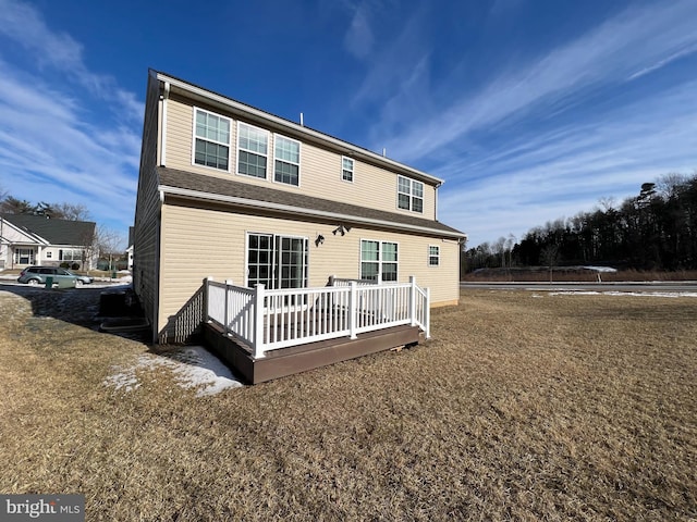 rear view of house featuring a wooden deck and a yard