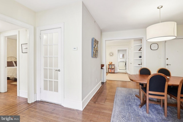 dining space featuring built in shelves, baseboards, and wood finished floors