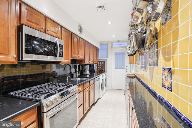 kitchen with appliances with stainless steel finishes, visible vents, a sink, and backsplash