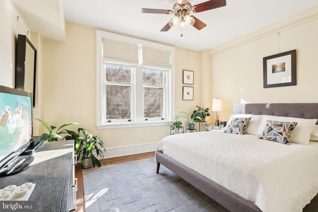 bedroom with wood finished floors, a ceiling fan, and baseboards