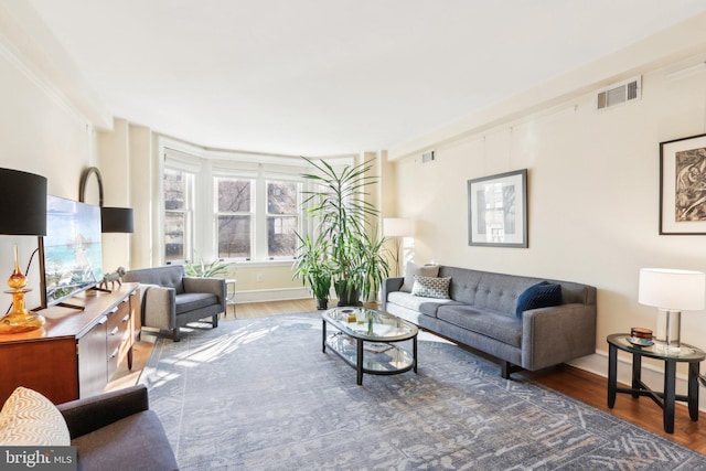 living room featuring visible vents, baseboards, and wood finished floors