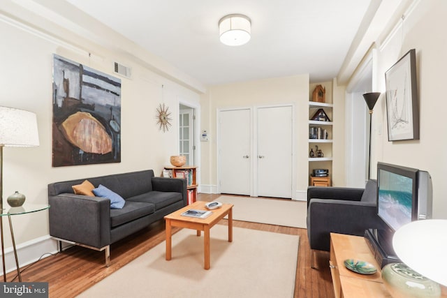 living area with visible vents, baseboards, and wood finished floors