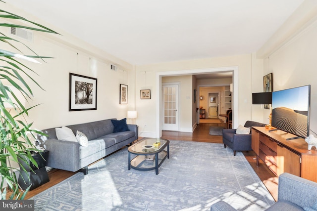 living room featuring visible vents, baseboards, and wood finished floors