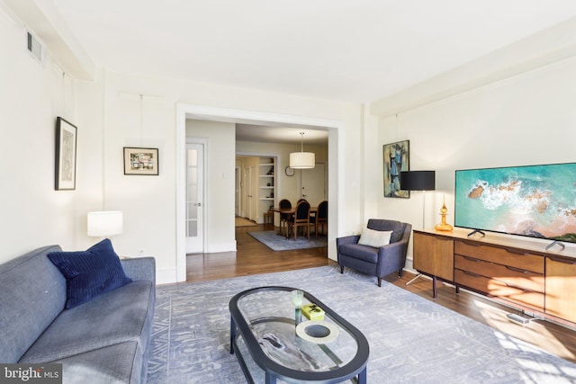 living area featuring wood finished floors, visible vents, and baseboards