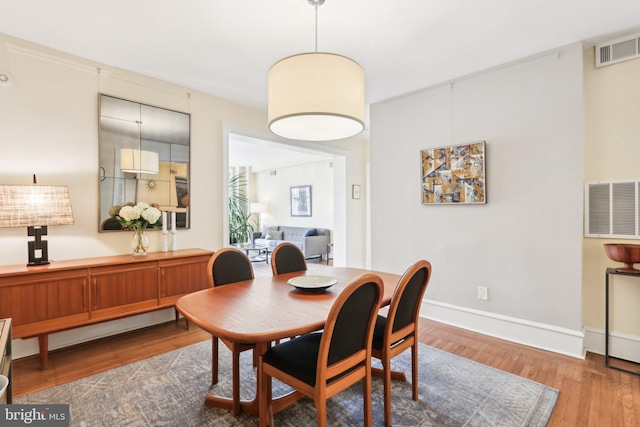 dining space featuring wood finished floors, visible vents, and baseboards