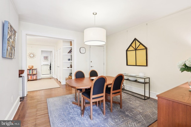 dining area featuring built in shelves, baseboards, and wood finished floors