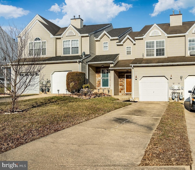 townhome / multi-family property with a chimney, concrete driveway, and an attached garage