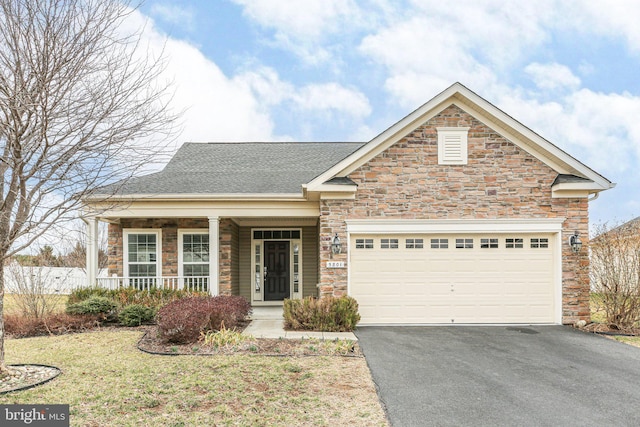 view of front of house featuring a shingled roof, aphalt driveway, covered porch, a garage, and stone siding