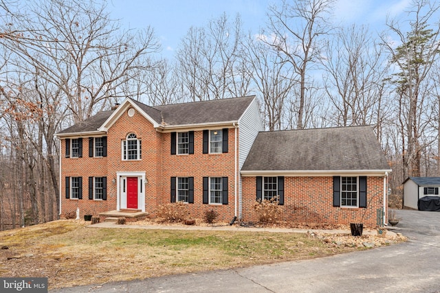 view of front facade featuring a front yard, brick siding, and roof with shingles