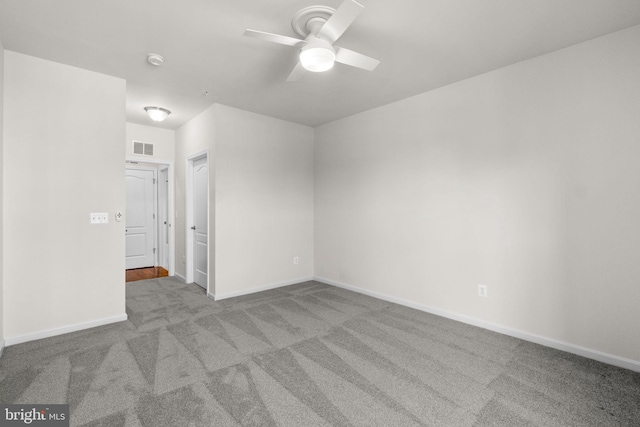 empty room featuring carpet floors, a ceiling fan, visible vents, and baseboards