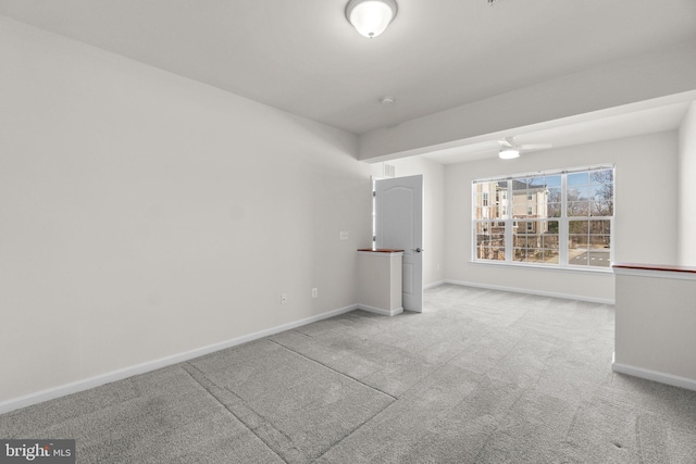 carpeted empty room with ceiling fan and baseboards