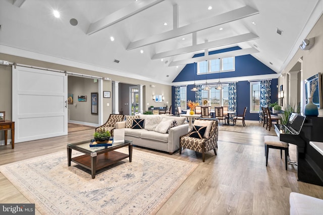 living room featuring high vaulted ceiling, light wood-style floors, decorative columns, and a barn door