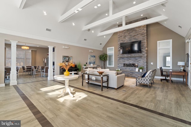 living area featuring high vaulted ceiling, wood finished floors, visible vents, beam ceiling, and decorative columns