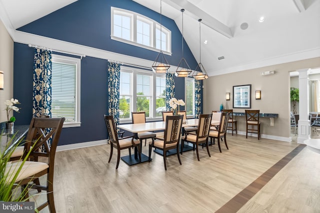 dining space featuring ornate columns, baseboards, light wood finished floors, and high vaulted ceiling