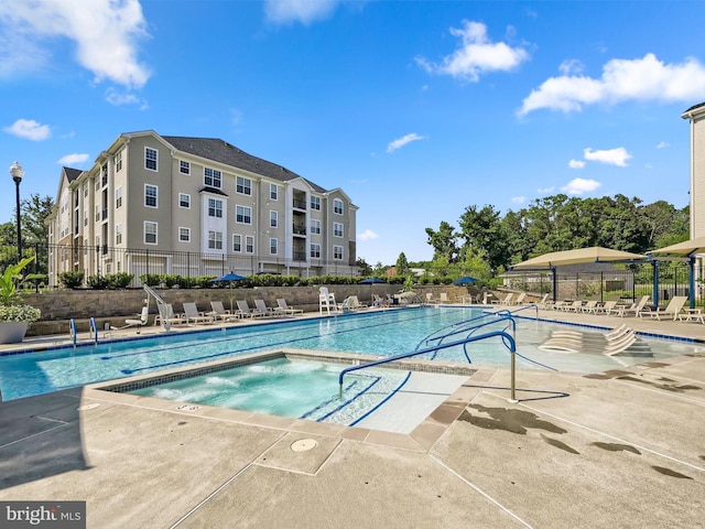 pool featuring a community hot tub, a patio area, and fence