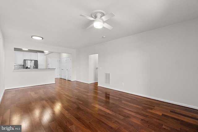 unfurnished living room with a ceiling fan, visible vents, dark wood finished floors, and baseboards