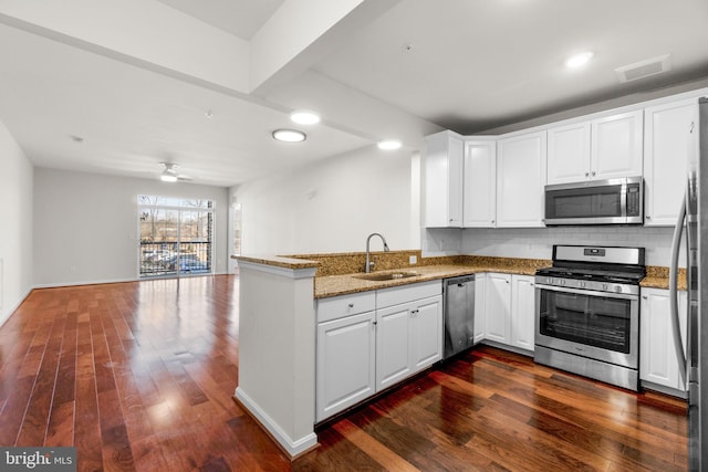 kitchen featuring dark wood-style flooring, stainless steel appliances, visible vents, white cabinets, and a sink