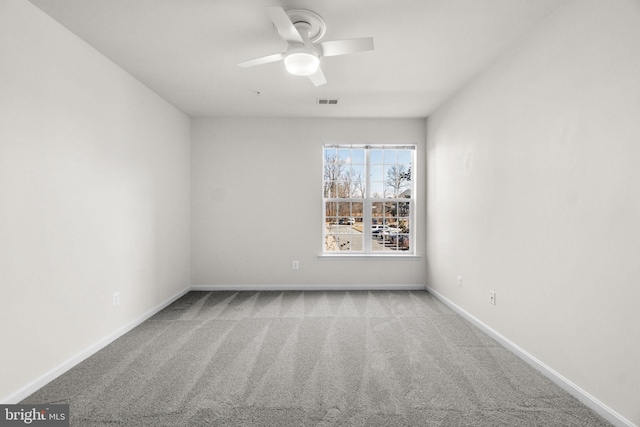 carpeted spare room featuring a ceiling fan, visible vents, and baseboards