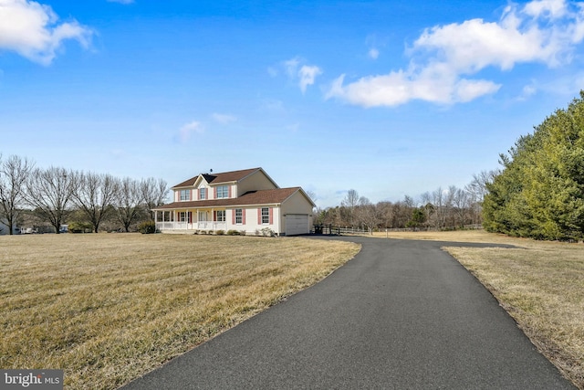 view of front of property featuring a porch, a garage, a front lawn, and aphalt driveway