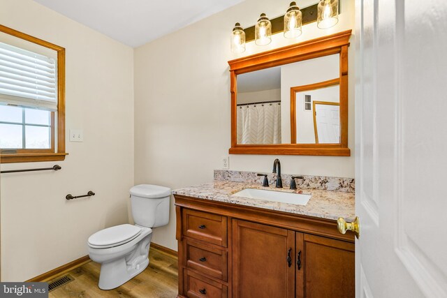 full bathroom with visible vents, baseboards, toilet, wood finished floors, and vanity