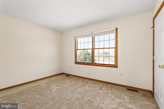 spare room with carpet, visible vents, and baseboards