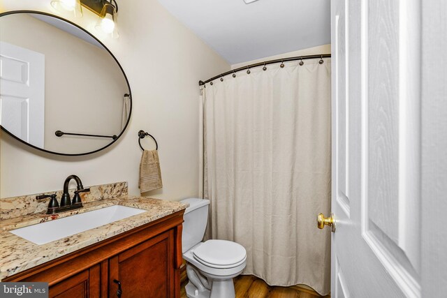 bathroom with toilet, wood finished floors, and vanity