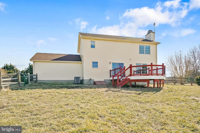 rear view of property with a deck, central air condition unit, fence, a yard, and a chimney