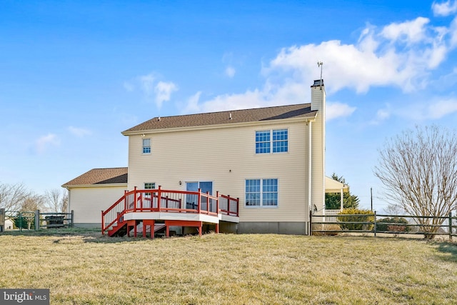 rear view of property featuring a lawn, a chimney, a wooden deck, and a fenced backyard