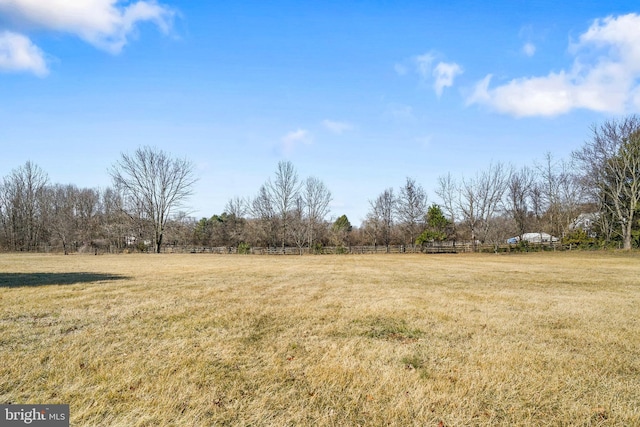 view of yard with fence and a rural view