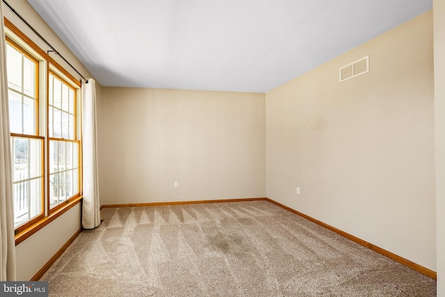 empty room featuring baseboards, light colored carpet, visible vents, and a healthy amount of sunlight