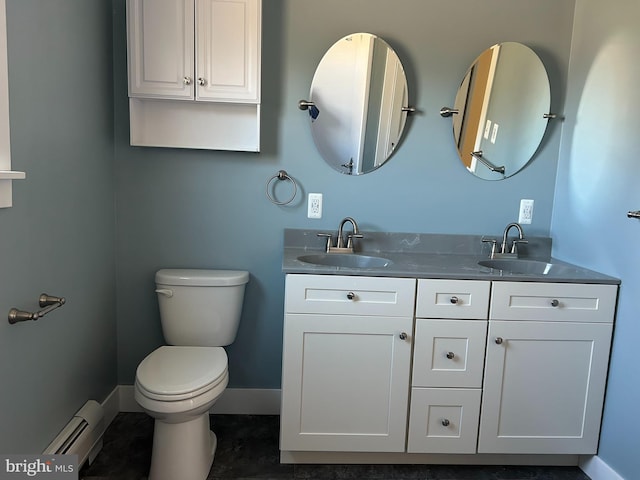 bathroom with toilet, a sink, baseboard heating, and double vanity