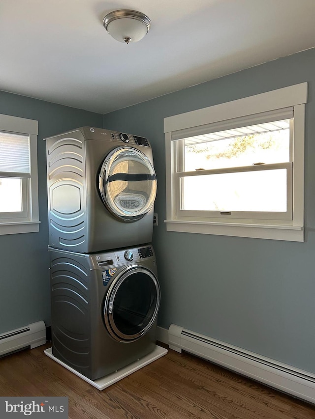 laundry room with a baseboard radiator, laundry area, stacked washing maching and dryer, and wood finished floors