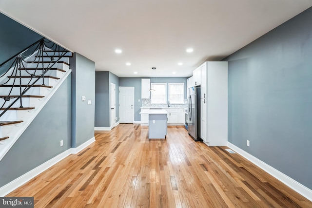 kitchen featuring white cabinetry, light wood-style floors, light countertops, freestanding refrigerator, and tasteful backsplash