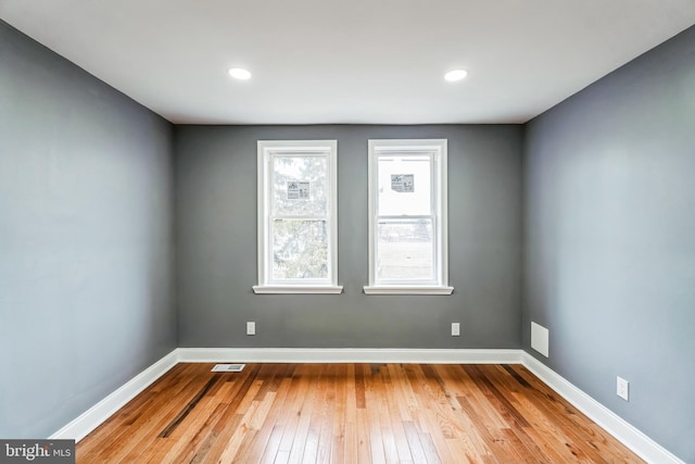 unfurnished room featuring wood-type flooring, visible vents, baseboards, and recessed lighting