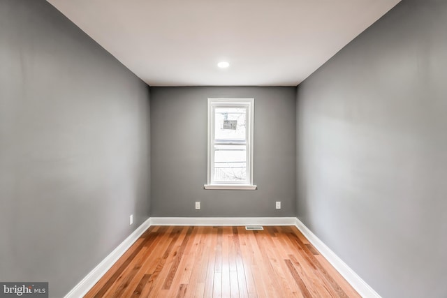 unfurnished room with light wood-type flooring, visible vents, and baseboards