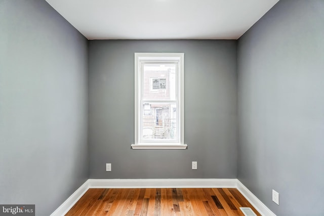 empty room featuring visible vents, baseboards, and wood finished floors