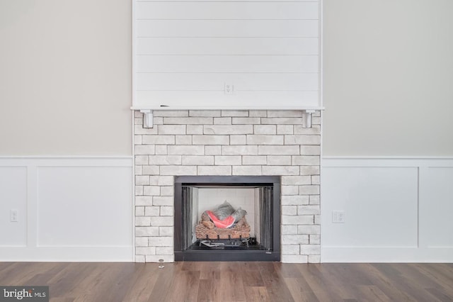 room details featuring a wainscoted wall, a fireplace, and wood finished floors