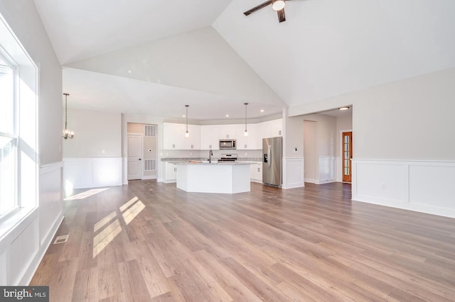 unfurnished living room featuring a sink, light wood-style floors, a decorative wall, and a wealth of natural light