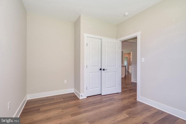 unfurnished bedroom with a closet, wood finished floors, and baseboards