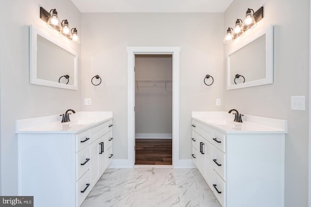 full bath with marble finish floor, two vanities, and a sink