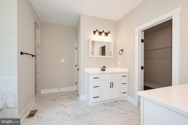 full bath featuring vanity, visible vents, baseboards, marble finish floor, and a spacious closet